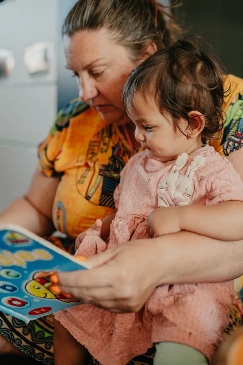 De gastouder leest samen met een peuter een telboek