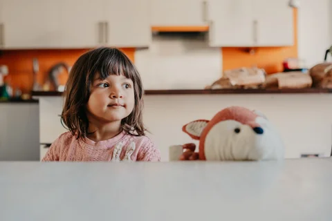 Een kind staat in de keuken, met de kenmerkende oranje accenten op de achtergrond