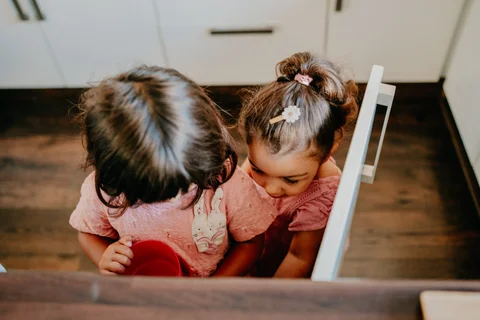 Twee kinderen kijken samen aandachtig naar iets op tafel