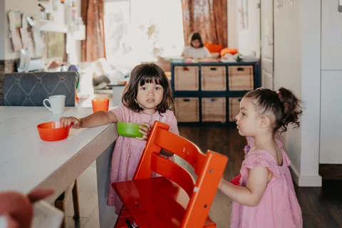 Twee kinderen zitten samen aan tafel in de lichte woonkamer