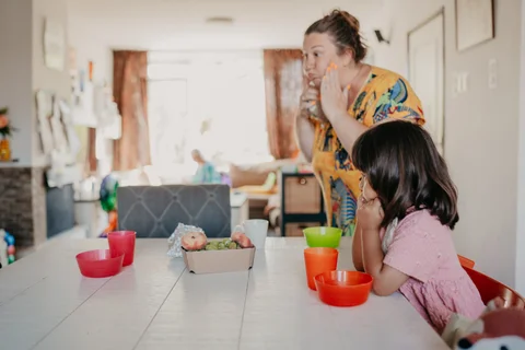 De gastouder zit samen met de kinderen aan tafel tijdens het fruitmoment