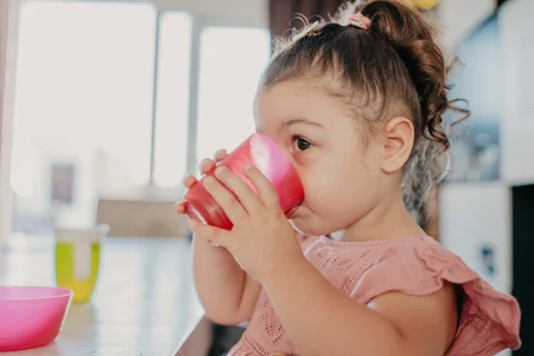 Een kind drinkt uit een bekertje tijdens het fruitmoment