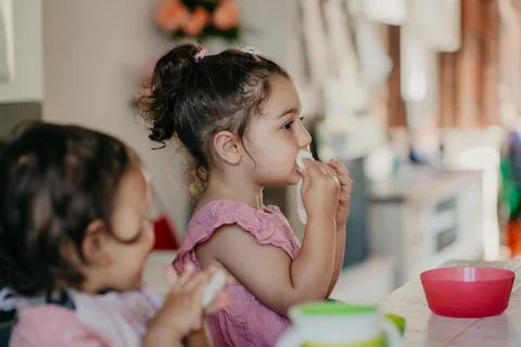 Een kind eet een snack, in profiel gefotografeerd