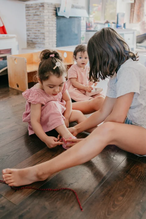 Twee kinderen zitten samen op de vloer terwijl de schoenen worden aangetrokken