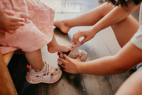 Een volwassene helpt een kind de schoenen aan te trekken