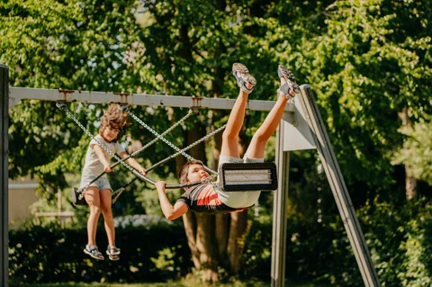 Een kind speelt actief op de schommel