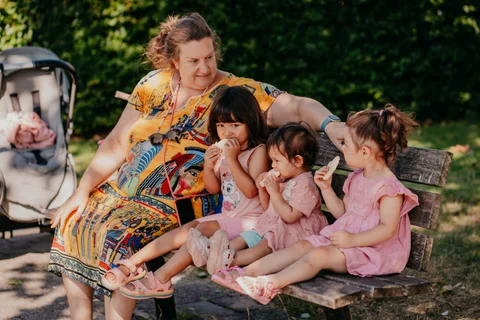 De gastouder zit samen met de kinderen op een bankje