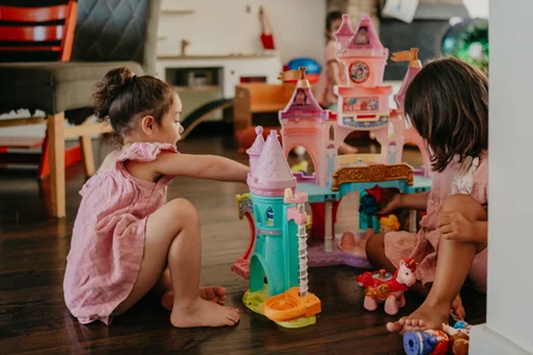 Twee kinderen spelen samen met een speelkasteel op de houten vloer van de woonkamer